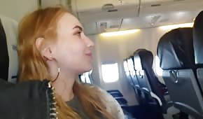 Una ragazza dai capelli rossi sta facendo un pompino sull'aereo